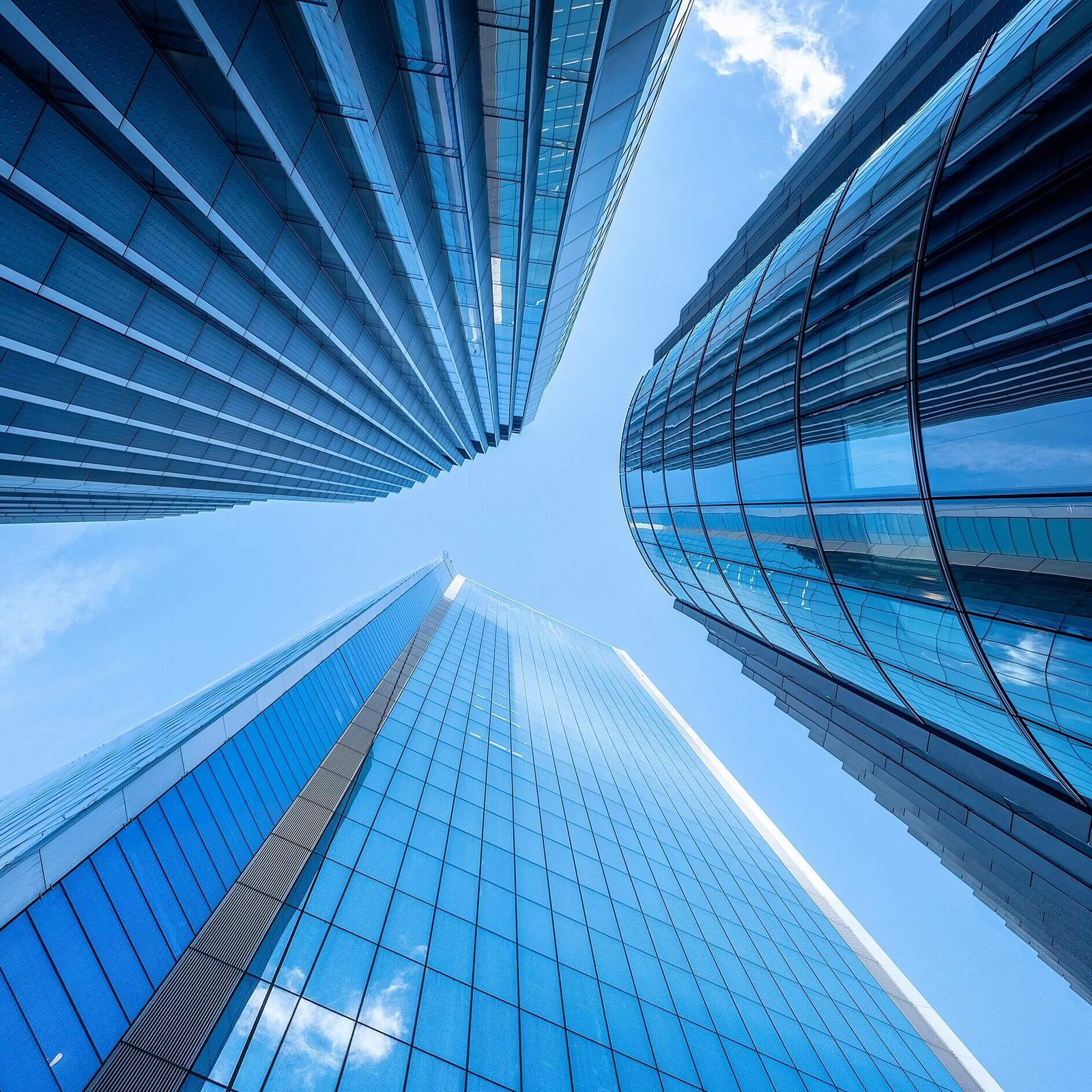 Glass office towers seen from below against a blue sky